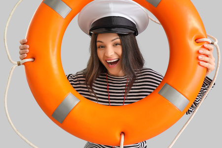 Female beach rescuer with lifebuoy on gray background