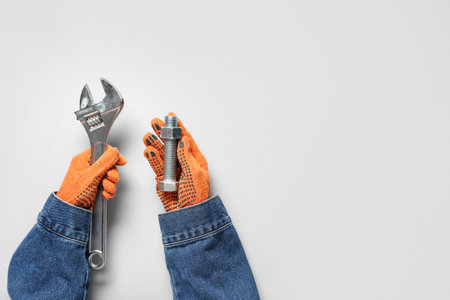 Mechanic's hands holding bolt and wrench on gray backgroundの写真素材