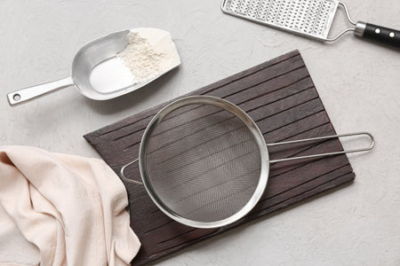 Wooden board with metal sieve, flour and grater on grunge backgroundの写真素材