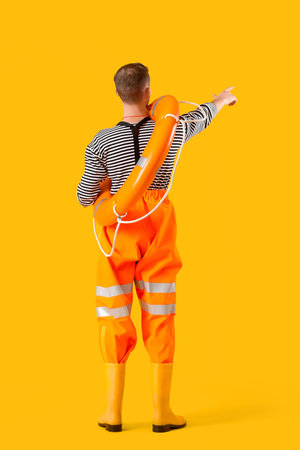 Male sailor with rescue ring on yellow background, back viewの写真素材
