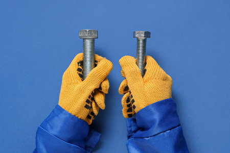 Mechanic's hands holding bolts on blue backgroundの写真素材