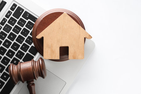 House figure with auction gavel and laptop on white backgroundの写真素材