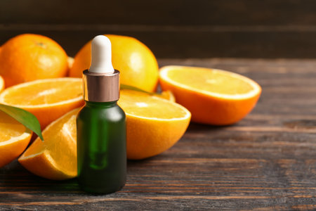 Bottle of orange essential oil with fresh fruits on wooden backgroundの写真素材
