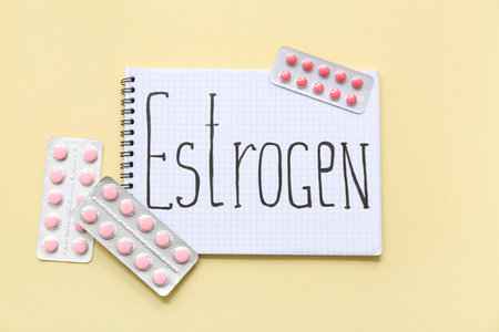 Notebook with the word ESTROGEN and blisters of hormonal pills on beige backgroundの写真素材