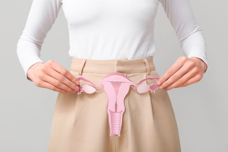 Woman holding paper uterus on light background