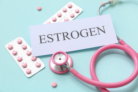 Word ESTROGEN with stethoscope and blisters of hormonal pills on turquoise backgroundの写真素材