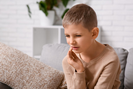 Little boy suffering from toothache at homeの写真素材