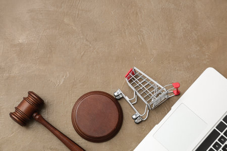 Auction gavel with shopping cart and laptop on beige grunge backgroundの写真素材