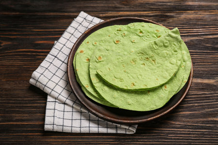 Plate with round green lavash on wooden backgroundの写真素材