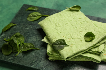 Board with fresh lavash and spinach on green grunge backgroundの写真素材