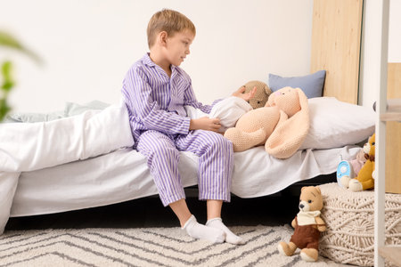 Cute little boy telling story to knitted toys in bedroomの写真素材