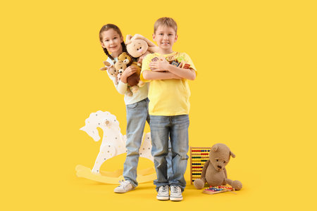 Cute little children with toys on yellow backgroundの写真素材