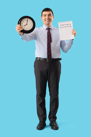 Young businessman with clock and calendar on blue background. Time management conceptの写真素材
