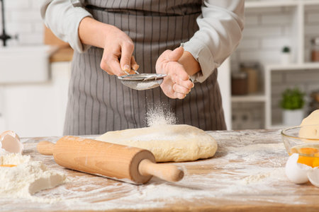 Woman kneading fresh dough in kitchen