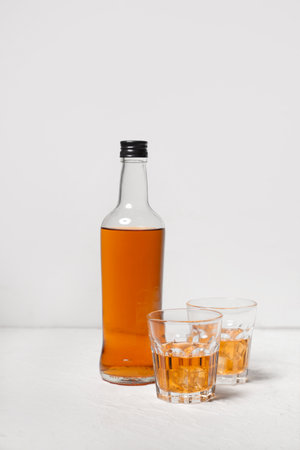 Bottle and glasses of rum with ice cubes on white backgroundの写真素材