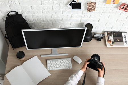 Female photographer with camera at table in office, top viewの写真素材