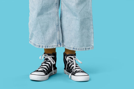 Teenage girl in sneakers on blue background, closeup