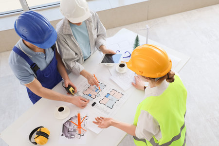 Team of constructors working with house plan at table in office