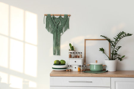 Jars with different spices, dishes and plants on counter near light wall in kitchenの写真素材