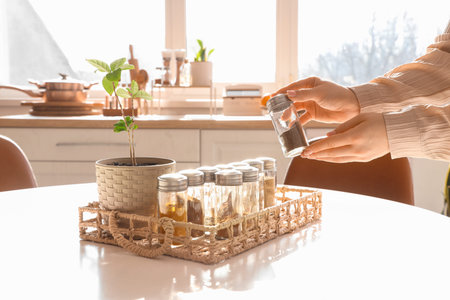 Woman taking spices from tray on table in kitchen, closeup