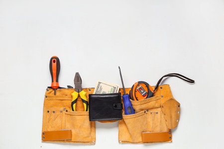 Wallet with money and tool belt on white background