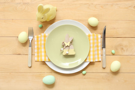 Beautiful table setting with Easter eggs and bunnies on wooden background