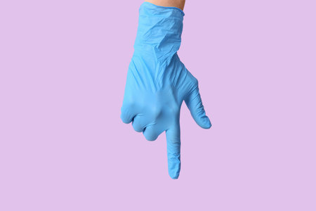 Female hand in medical glove pointing at something on lilac background