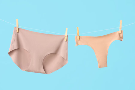 Female panties hanging on clothesline against blue backgroundの写真素材