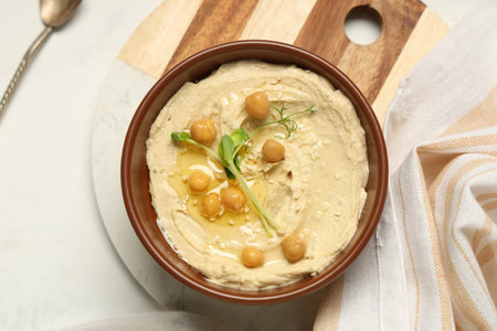 Bowl of delicious hummus with chickpeas, sesame seeds and micro green on light backgroundの写真素材