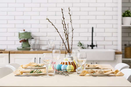 Festive table setting with willow branches, painted eggs and Easter cake in kitchenの写真素材