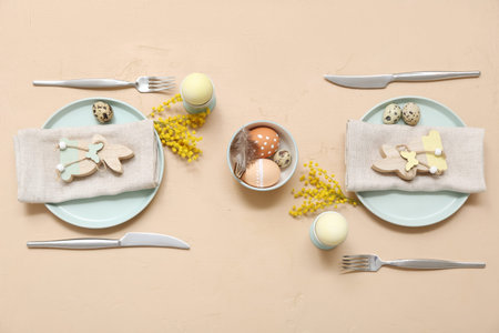 Beautiful table setting with Easter eggs and mimosa flowers on beige background