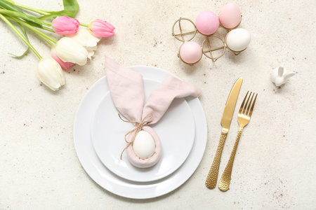 Beautiful table setting with Easter eggs and tulip flowers on white backgroundの写真素材