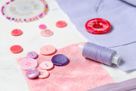 Different colorful buttons with sewing supplies and fabric samples on white background