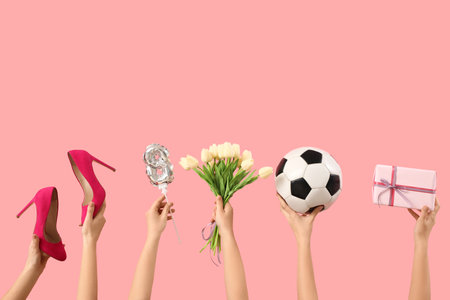 Female hands with figure 8 made of balloon, flowers, soccer ball and gift box on pink background. International Women's Day celebrationの写真素材