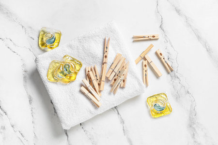Wooden clothespins with clean towel and gel capsules on grunge white background