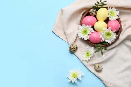 Bowl with Easter eggs, flowers and napkin on blue backgroundの写真素材