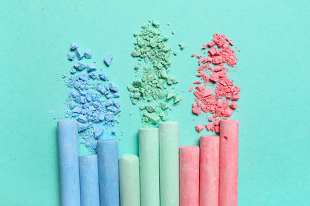 Colorful chalks with crushed pigments on turquoise background