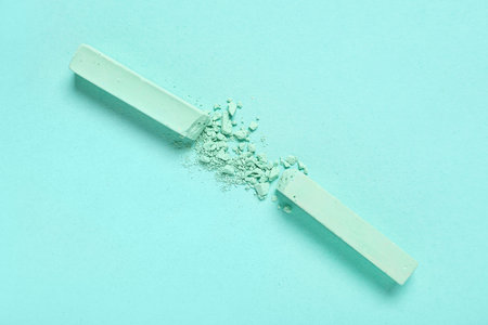 Green chalks with crushed pigment on turquoise background
