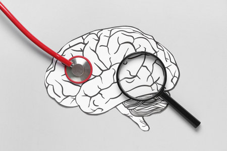 Paper human brain with stethoscope and magnifying glass on gray background. Cancer concept
