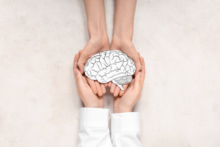 Female hands holding paper human brain on light background. Cancer conceptの写真素材
