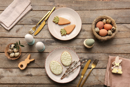 Beautiful table setting with sweet cookies, Easter eggs and pussy willow branches on wooden backgroundの写真素材