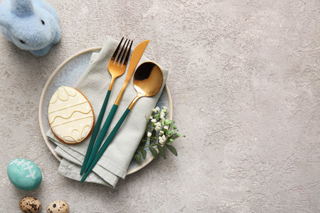 Beautiful table setting with sweet cookie, Easter eggs, toy rabbit and gypsophila flowers on gray backgroundの写真素材