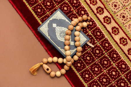 Koran with prayer beads and rug on brown background. Ramadan celebration
