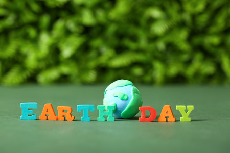 Text EARTH DAY with planet made of plasticine on green table outdoors, closeupの写真素材