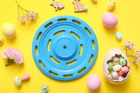 Composition with frisbee, Easter eggs, decor and flowers on yellow backgroundの写真素材