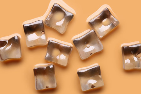 Texture of coffee with milk and ice cubes as background, top view