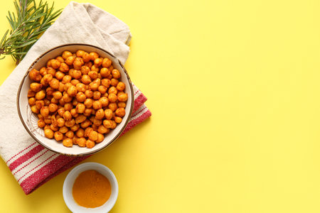 Bowl of tasty fried chickpeas with rosemary and spices on yellow backgroundの写真素材