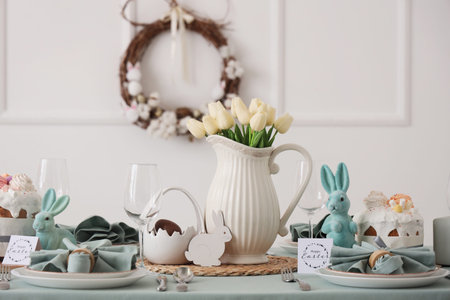 Tulip flowers, Easter cake and decorative rabbits on served table for Easter celebration. Closeup