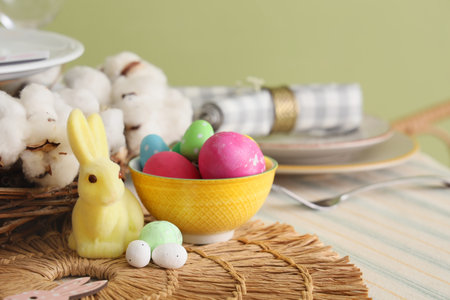Painted eggs in bowl and rabbit on table served for Easter celebration. Closeup