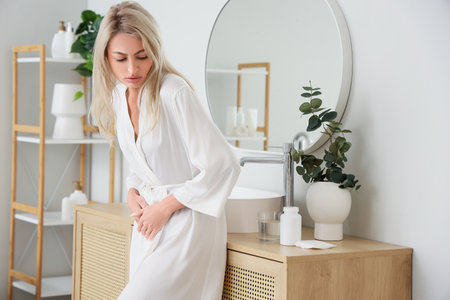 Young woman suffering from menstrual cramps in bathroomの写真素材